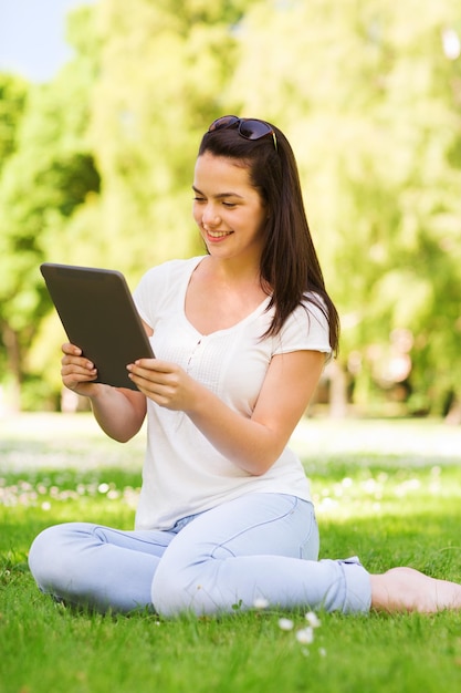 concetto di stile di vita, estate, vacanze, tecnologia e persone - ragazza sorridente con computer tablet pc seduto sull'erba nel parco