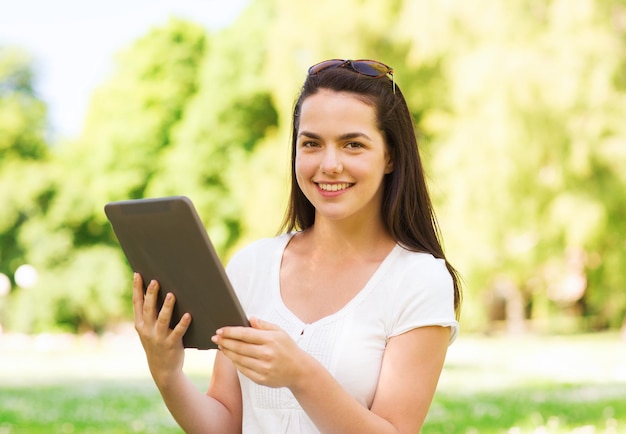 concetto di stile di vita, estate, vacanze, tecnologia e persone - ragazza sorridente con computer tablet pc seduto sull'erba nel parco