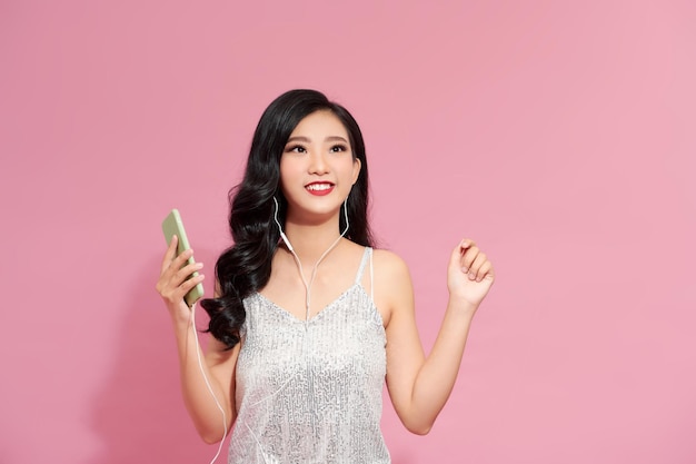 Concetto di stile di vita Ritratto di bella donna asiatica gioiosa che ascolta la musica sul telefono cellulare
