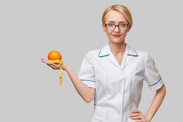 concetto di stile di vita sano medico nutrizionista - tenendo la frutta arancione fresca organica e metro a nastro