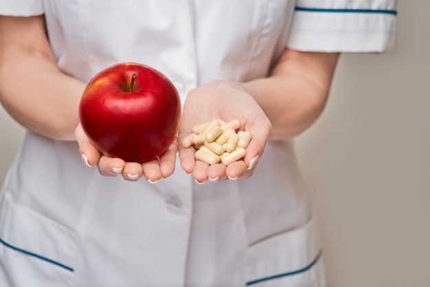 concetto di stile di vita sano medico nutrizionista - tenendo organica mela rossa e vitamina o capsule di medicina pillole