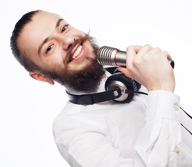 Concetto di stile di vita: un giovane con la barba che indossa una camicia bianca con in mano un microfono e canta.Isolato su bianco.