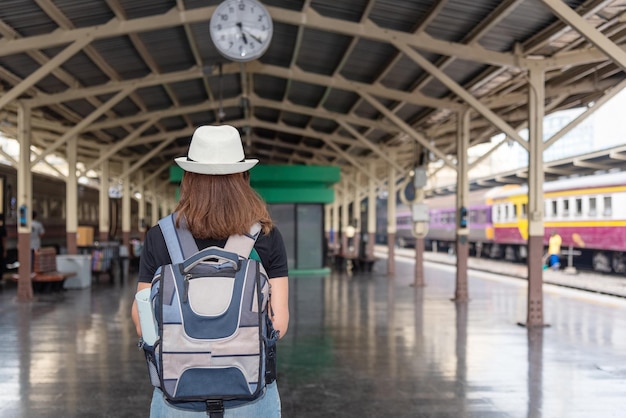 Concetto di stile di vita vacanze viaggio o viaggio Giovane donna asiatica zaino in spalla e indossare un cappello bianco sta camminando per prendere un treno alla stazione