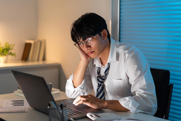 Concetto di superlavoro L'ufficiale maschio appoggia il viso sulla mano destra e fa una faccia stressante.