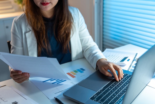 Concetto di superlavoro La donna che fa il suo lavoro a tarda notte leggendo documenti e digitandoli