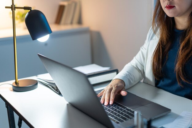 Concetto di superlavoro La donna che lavora in ufficio e digita qualcosa sul computer portatile