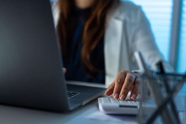 Concetto di superlavoro La donna che lavora in ufficio e digita qualcosa sul computer portatile