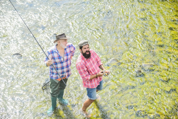 Concetto di svago di una vacanza rurale hobby natura selvaggia due felice pescatore con canna da pesca e rete Big game pesca amicizia padre e figlio pesca bracconaggio campeggio sulla riva del lago