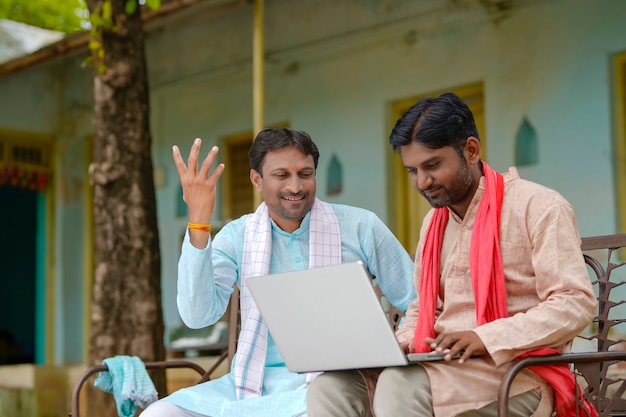 Concetto di tecnologia: agricoltori indiani che utilizzano laptop a casa.
