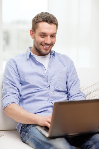 concetto di tecnologia, casa e stile di vita - uomo sorridente che lavora con il laptop a casa