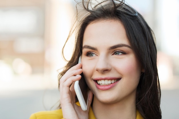 concetto di tecnologia, comunicazione e persone - giovane donna o ragazza sorridente che chiama smartphone sulla strada della città