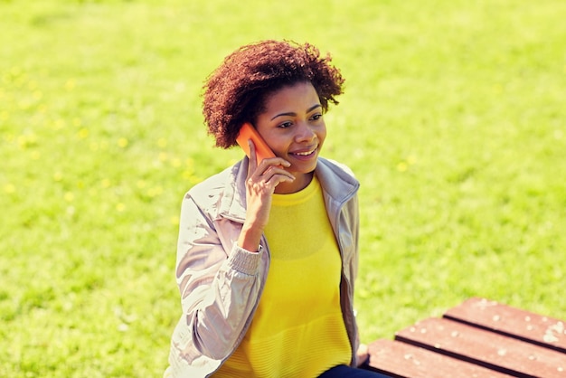 concetto di tecnologia, comunicazione e persone - sorridente giovane donna afroamericana o ragazza adolescente che chiama smartphone all'aperto