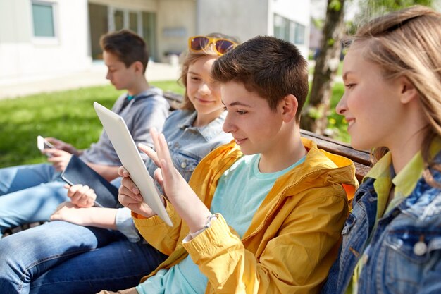 concetto di tecnologia, internet e persone - gruppo di amici o studenti adolescenti felici con computer tablet pc all'aperto