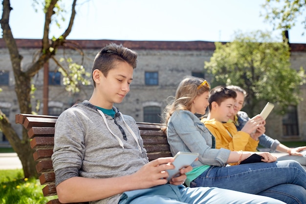 concetto di tecnologia, internet e persone - gruppo di amici o studenti adolescenti felici con computer tablet pc all'aperto