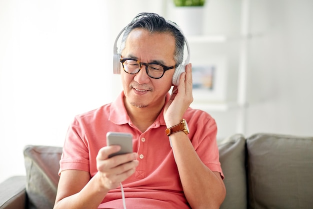 concetto di tecnologia, persone e stile di vita - uomo felice con smartphone e cuffie che ascolta la musica a casa