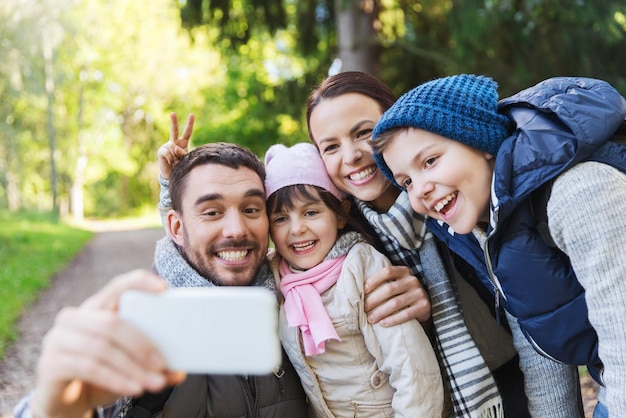 concetto di tecnologia, viaggi, turismo, escursione e persone - famiglia felice con zaini che prendono selfie con smartphone ed escursioni