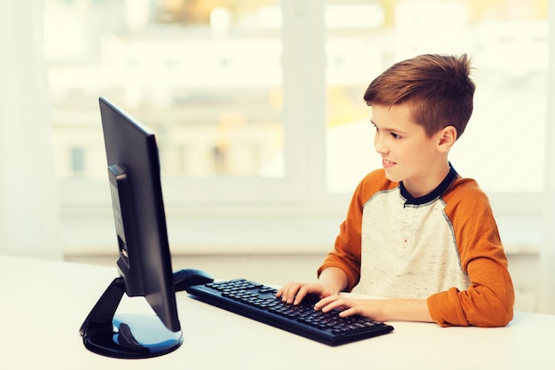 concetto di tempo libero, bambini, istruzione, tecnologia e persone - ragazzo sorridente con il computer a casa