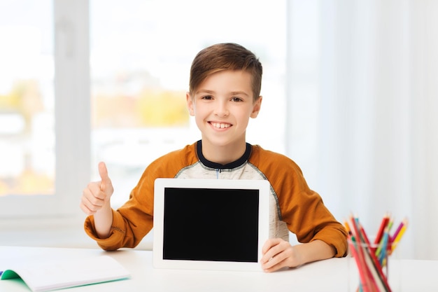 concetto di tempo libero, bambini, tecnologia, istruzione e persone - ragazzo sorridente che mostra lo schermo del computer tablet pc vuoto e mostra i pollici in su a casa