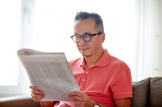 concetto di tempo libero, informazione, persone e mass media - uomo felice con gli occhiali che legge il giornale a casa
