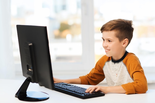 concetto di tempo libero, istruzione, bambini, tecnologia e persone - ragazzo sorridente con il computer a casa