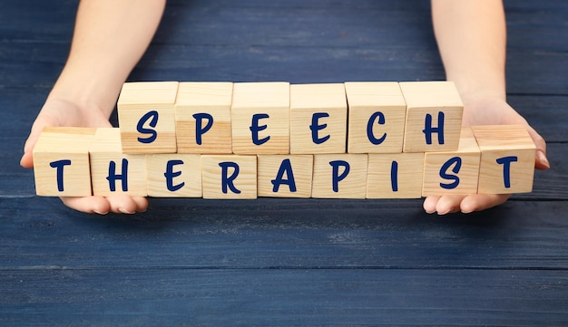 Concetto di terapia vocale Mani che tengono i cubi su sfondo di legno