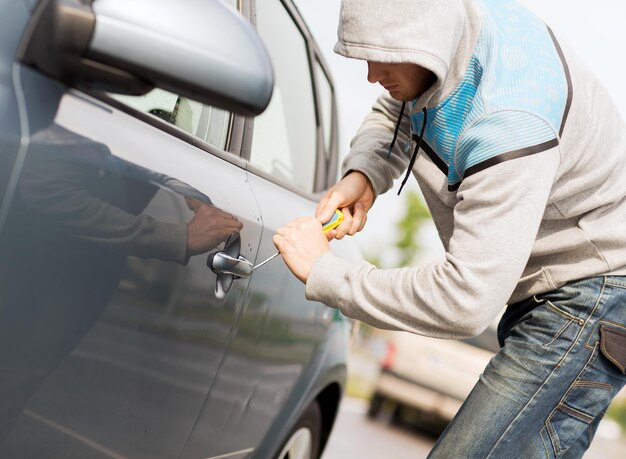 concetto di trasporto, criminalità e proprietà - ladro che rompe la serratura dell'auto