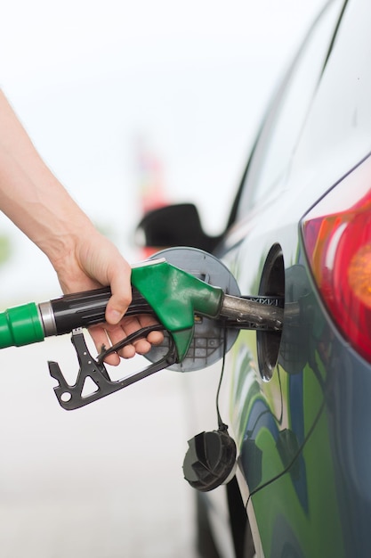 concetto di trasporto e proprietà - uomo che pompa benzina in auto alla stazione di servizio