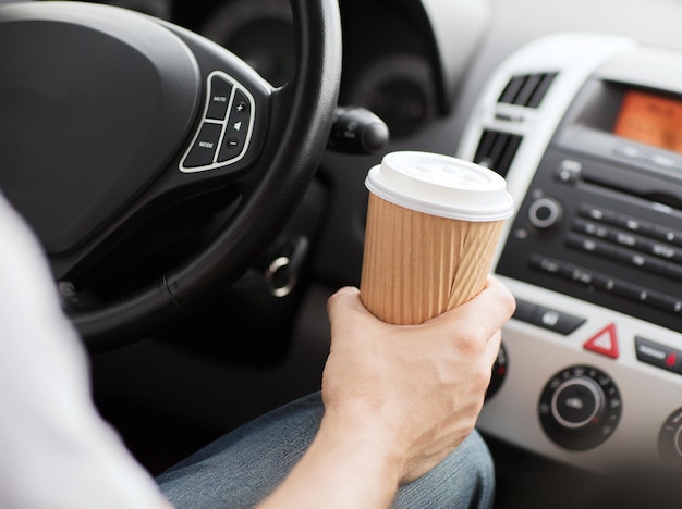 concetto di trasporto e veicolo - uomo che beve caffè mentre guida l'auto