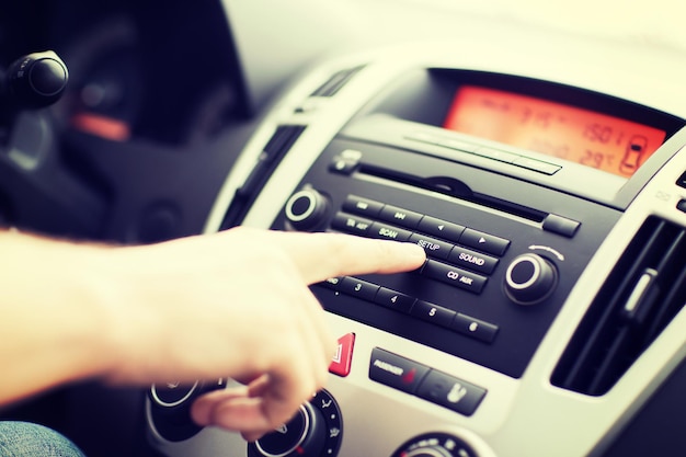 concetto di trasporto e veicolo - uomo che utilizza l'impianto stereo dell'auto