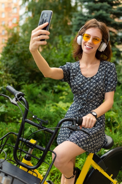 concetto di trasporto ecologico. carina ragazza europea cavalca una bicicletta a noleggio nel parco e prende un selfie