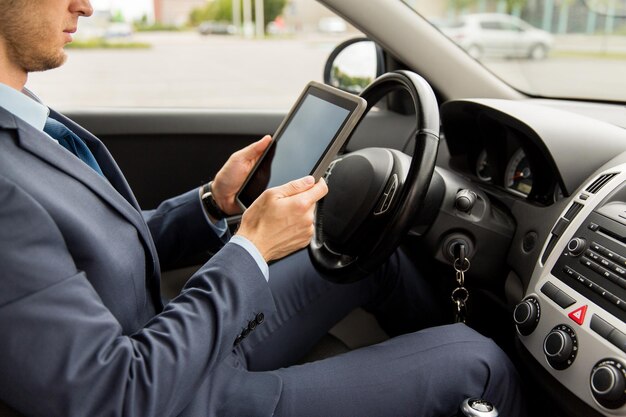 concetto di trasporto, viaggio d'affari, tecnologia e persone - primo piano di un giovane con computer tablet pc che guida l'auto