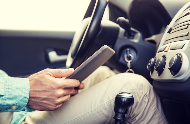 concetto di trasporto, viaggio d'affari, tecnologia e persone - primo piano di un giovane con computer tablet pc che guida l'auto