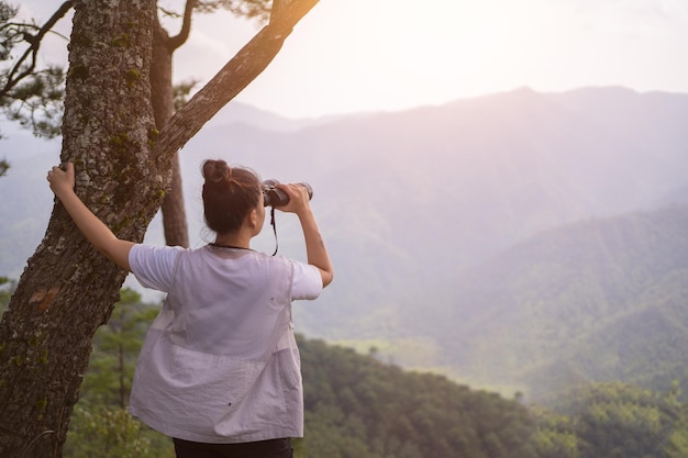 Concetto di trekking Le donne che fanno escursionismo usano il binocolo per viaggiare