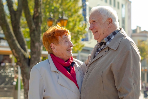 Concetto di turismo e persone in età familiare coppia senior felice che si tiene per mano e cammina per le strade autunnali della vecchia Europa