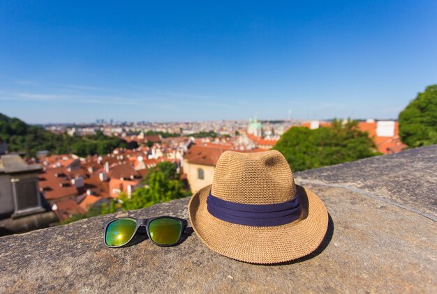 Concetto di turismo ed estate - Cappello e occhiali da sole contro una città vecchia.