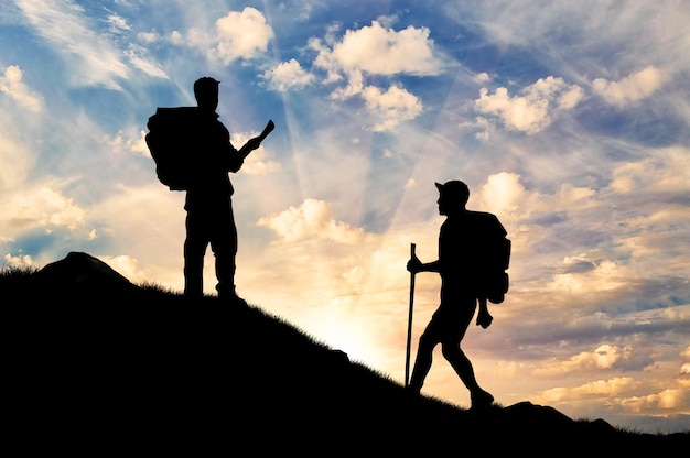 Concetto di turismo. Scalatori di sagoma che salgono sulla montagna al tramonto