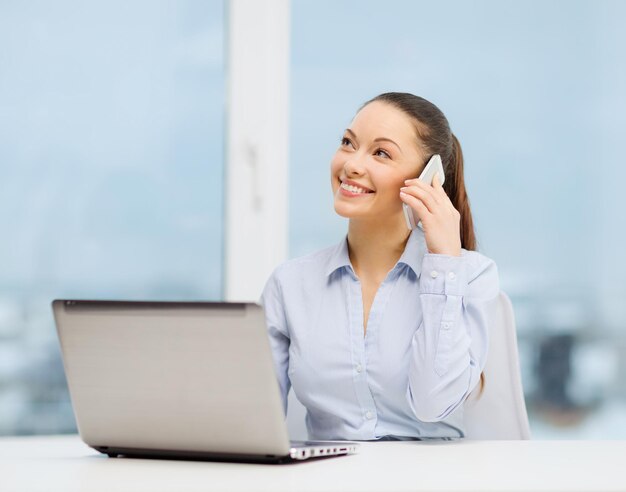 concetto di ufficio, affari e tecnologia - donna d'affari sorridente con computer portatile e smartphone