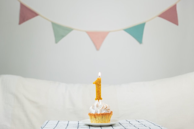 Concetto di un anno. "Una" candela di anniversario che brucia sopra una piccola torta in uno sfondo pulito decorato