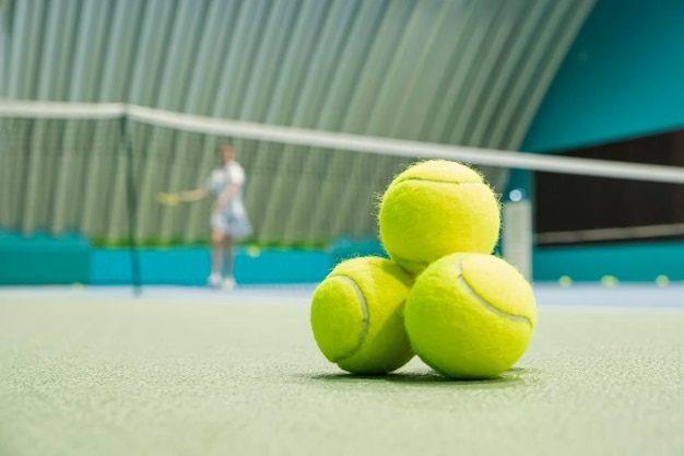 Concetto di uno stile di vita sportivo palline da tennis sul campo sul pavimento sullo sfondo di una ragazza pl