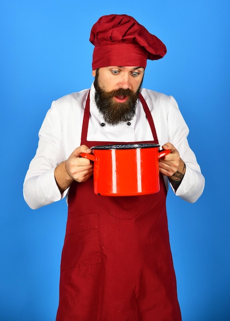 Concetto di utensili da cucina L'uomo con la barba tiene gli utensili da cucina