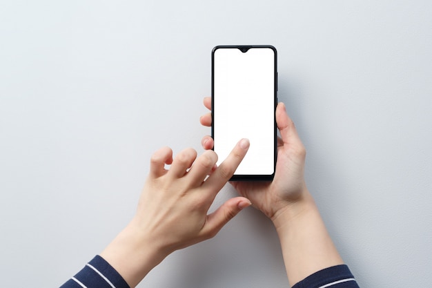 Concetto di utilizzo dello smartphone. smartphone con uno schermo bianco bianco nelle mani di una donna.