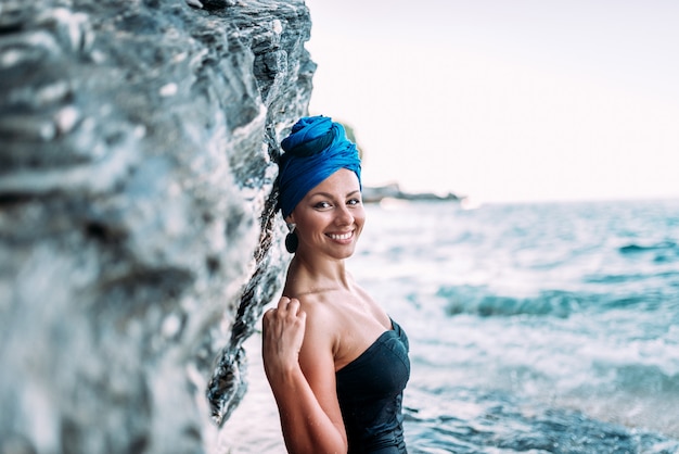 Concetto di vacanza estiva Bella donna che si appoggia sulla roccia vicino al mare. Sorriso genuino