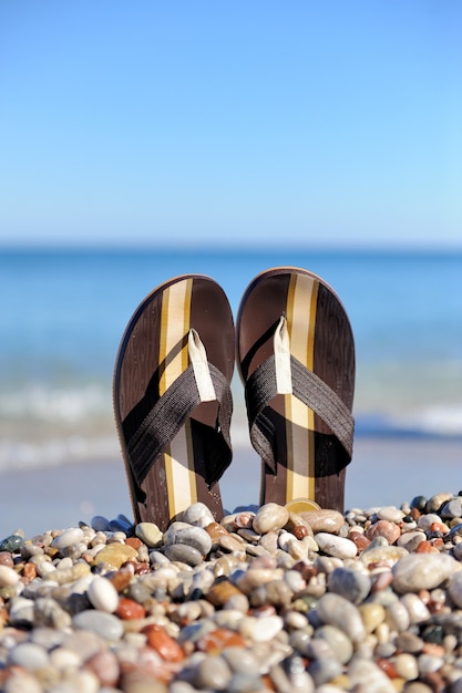 Concetto di vacanza estiva. Infradito in spiaggia oceanica di pietra