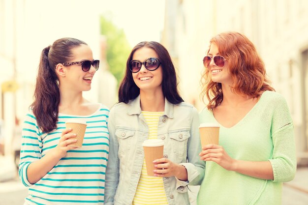 concetto di vacanza, fine settimana, bevande e amicizia - adolescenti sorridenti con tazze di caffè sulla strada