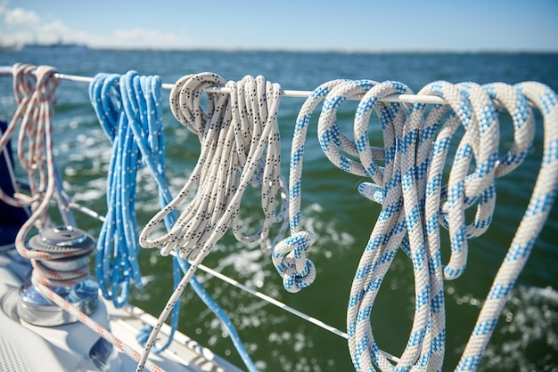 concetto di vacanza, viaggio, crociera e yachting - primo piano della corda di ormeggio sulla barca a vela o sul ponte e sul mare dello yacht a vela