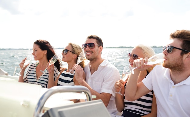 concetto di vacanza, viaggio, mare, amicizia e persone - amici sorridenti con bicchieri di champagne sullo yacht