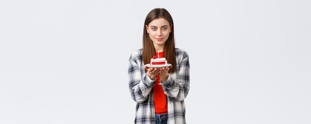 Concetto di vacanze di stile di vita della gente e concetto di emozioni di celebrazione La splendida giovane donna sognante festeggia il suo compleanno tenendo la torta bday con una candela accesa che sorride gentile alla macchina fotografica