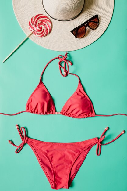 Concetto di vacanze estive con il costume da bagno del bikini di rosa della donna su fondo verde pallido