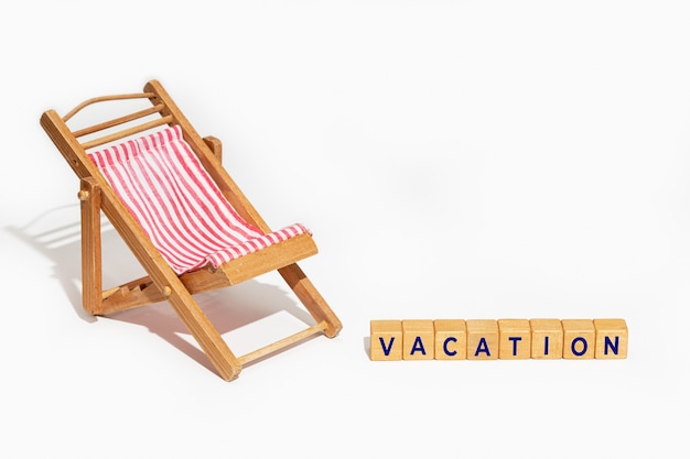 Concetto di vacanze estive. Sedia e blocchi di legno con la vacanza del testo isolata su fondo bianco.