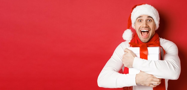 Concetto di vacanze invernali natale e stile di vita primo piano dell'uomo felice in cappello santa che riceve prese...